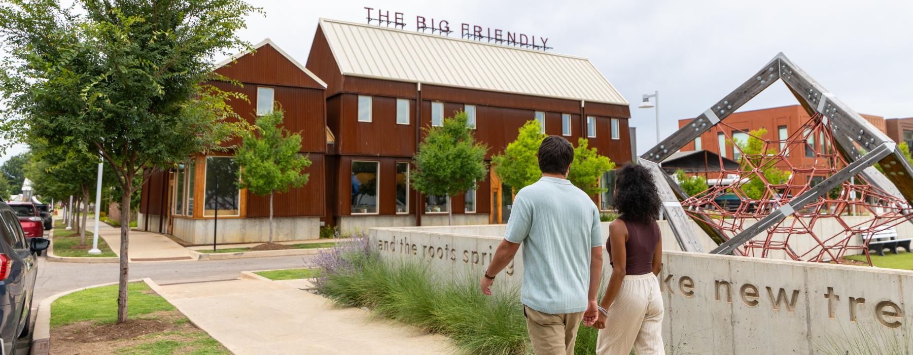 a man and woman walking down a sidewalk in front of a building